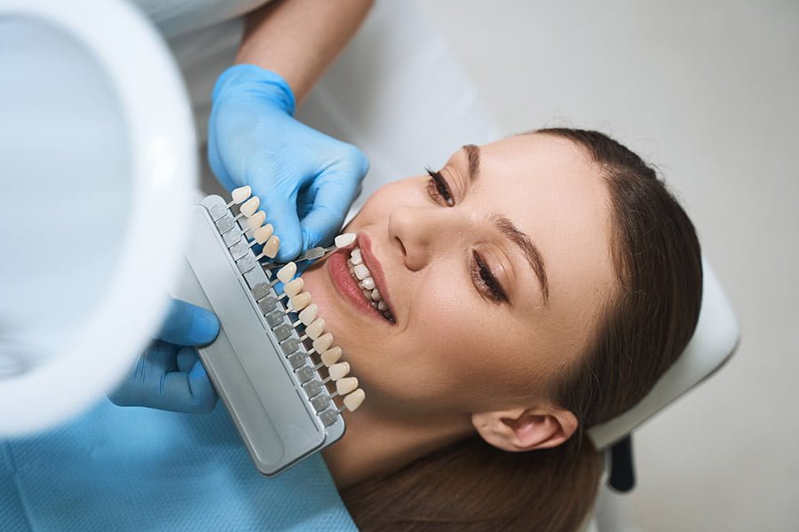 A dentist bonding a dental veneer onto a prepared tooth during a cosmetic procedure.